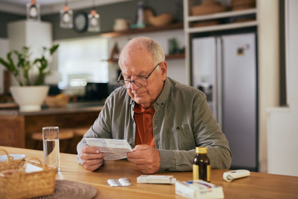 Senior qui étudie ses médicaments pouvant bloquer sa thermorégulation