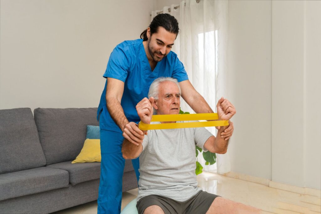 Senior qui fait de la gymnastique douce encadré par le kinésithérapeute