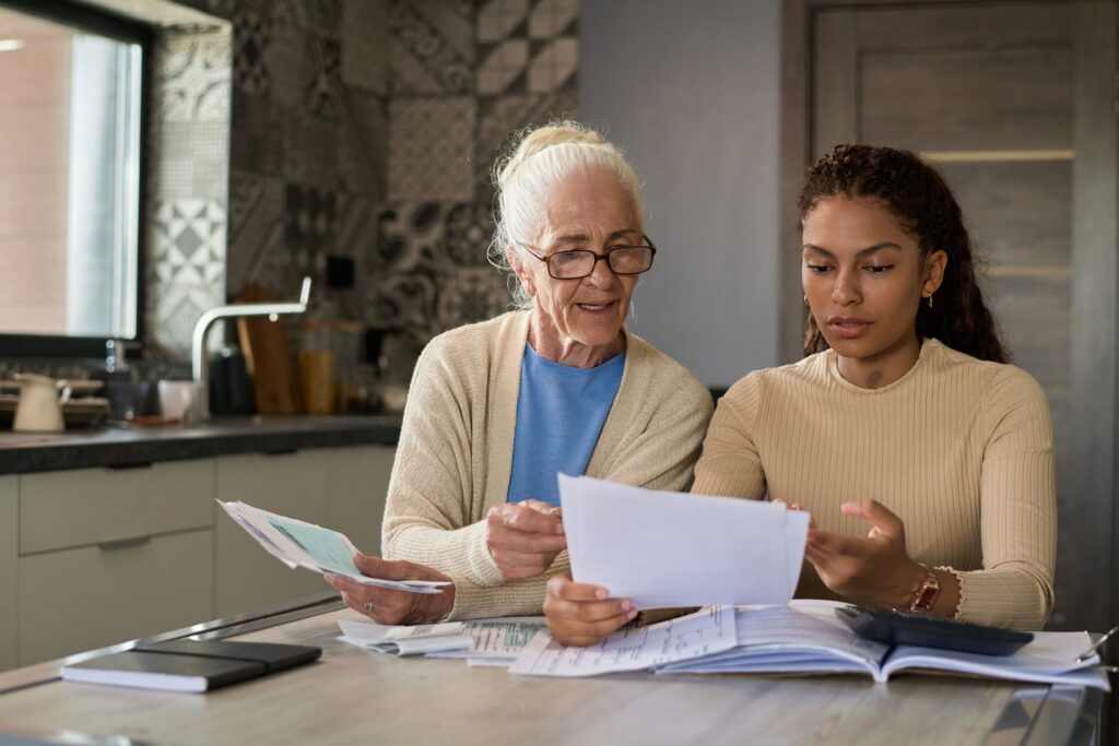 Senior et son aidante qui analysent les frais d'agence, dépôt de garantie et charges en résidence senior